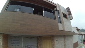 A two-story building with a sign for 'HOTEL Pousada Santa Cruz' and amenities listed including TV, air conditioning, parking, and a family-friendly environment. - Hotel e Pousada Santa Cruz (Aparecida)