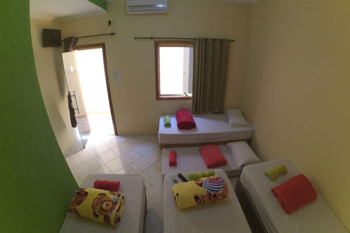 Une chambre d’hôtel avec deux lits, une fenêtre avec des rideaux, une porte et un appareil de climatisation.