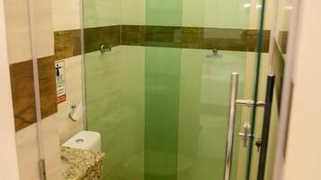Un baño pequeño y cerrado con cabina de ducha de vidrio, inodoro y lavabo.