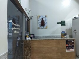 Un área de recepción con mostrador de madera, decoración mural de mármol y un letrero que indica la ubicación de Maxa Lotação.