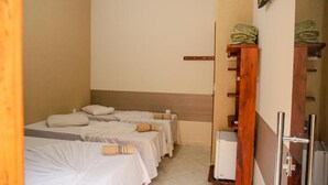 A hotel room with two beds, a wooden shelf with folded towels, a mirror, and a small white appliance. - Hotel e Pousada Santa Cruz (Aparecida)