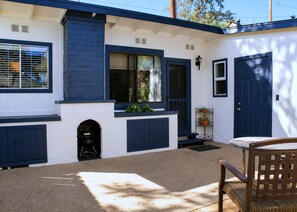 A house with a white exterior and dark blue trim, a front door, a small porch with a bench, and a window with a view of the outdoors. - Patio + BBQ + Downtown Access | Paso Robles | Vine Street Guest House (Paso Robles)