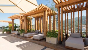 A rooftop terrace with wooden pergolas, cushioned seating areas, and potted plants. - Sail View,Spacious Condo Romantic Zone Ocean Views (Puerto Vallarta)