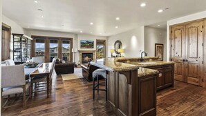 A spacious kitchen with a large island, wooden cabinets, and a dining area with a fireplace. - Ski-in Ski-out | Luxury | Chefs Kitchen | Garage (Park City)