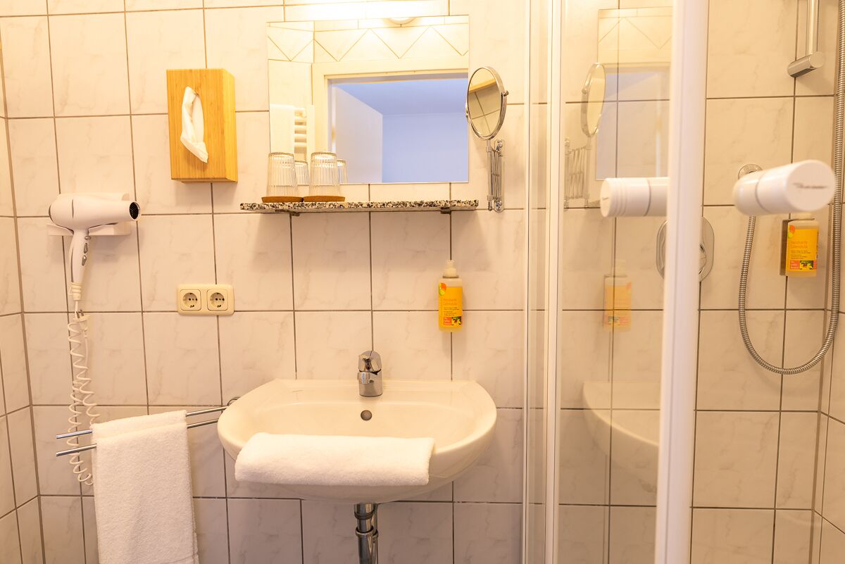 Ein Badezimmer mit Waschbecken, Spiegel, Handtuchhalter und Föhn.