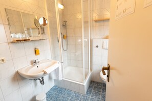 Tweepersoonskamer | Badkamer | Een douche, een haardroger, handdoeken, zeep