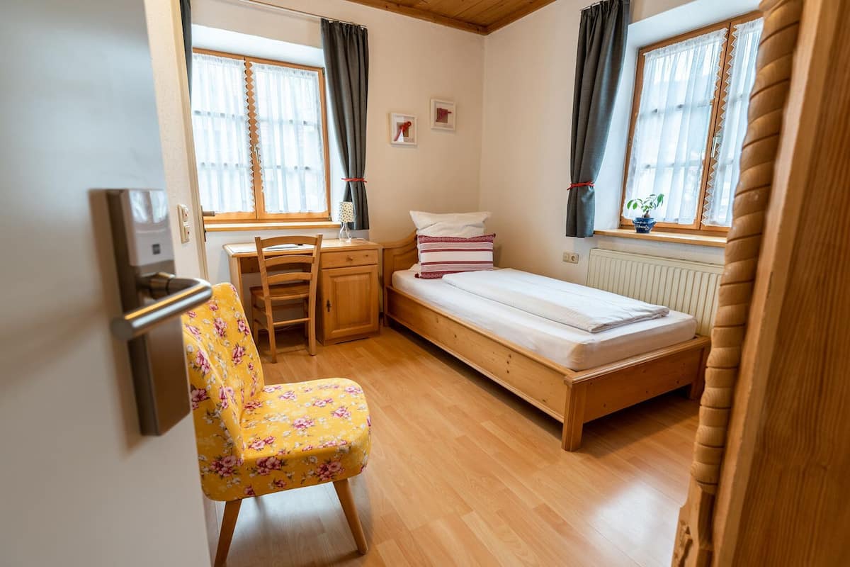 A small, cozy room with a single bed, a desk, and a chair.