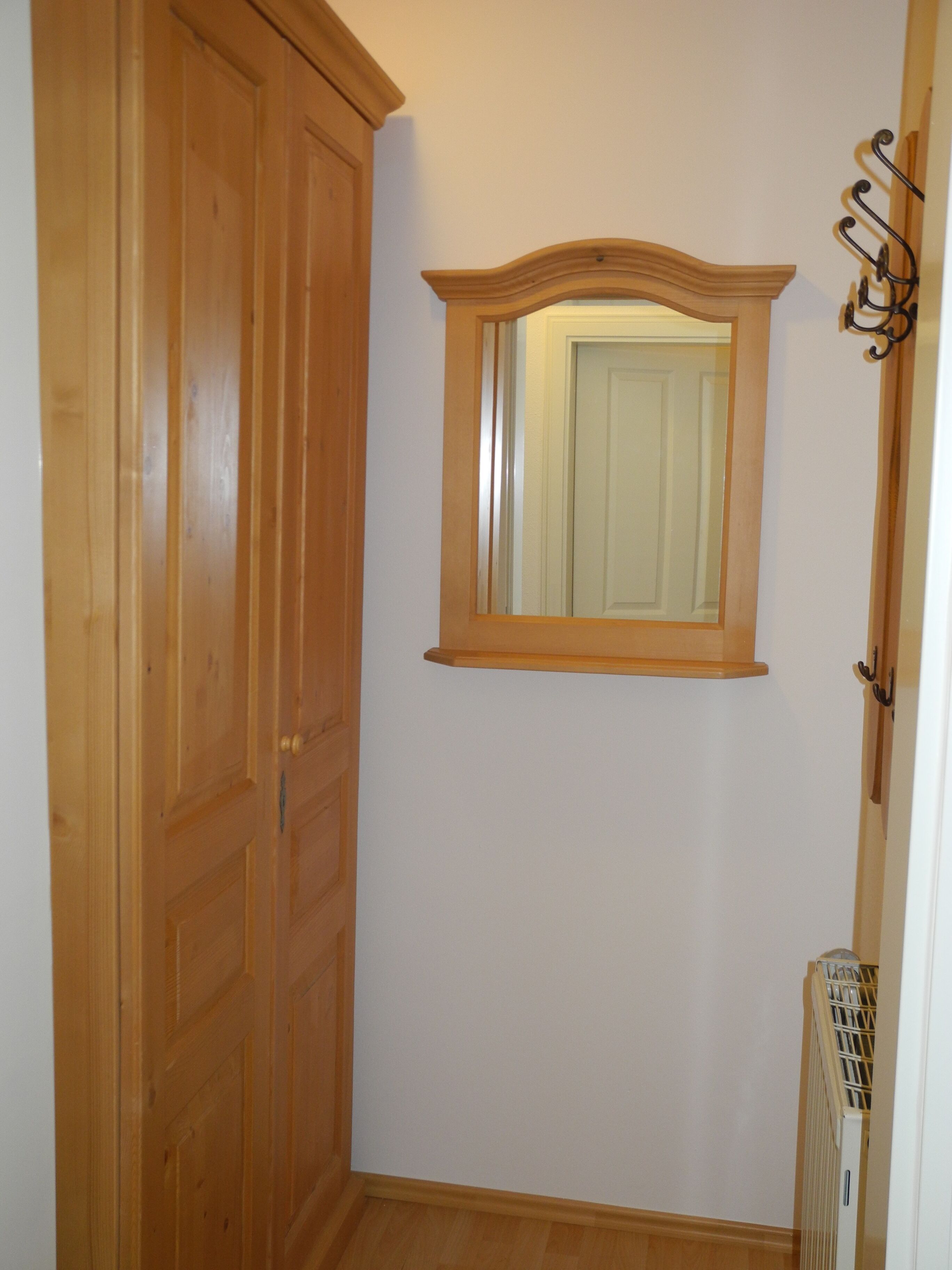 A hallway with wooden doors and a mirror on the wall.