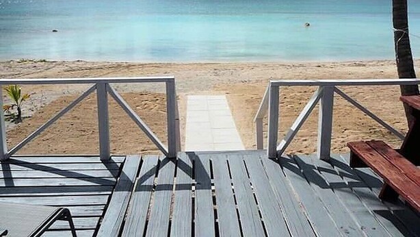 Una terraza de madera que da a una playa con vista despejada al océano.