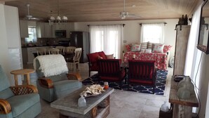 Amplia sala de estar con una mesa de comedor, sofás y una cocina al fondo.