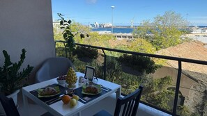 A balcony with a table set for two, overlooking a harbor with ships and cranes. - Location10 (Palermo)