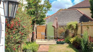 A garden with a wooden fence, a bench, a table, and a potted plant. - 1 bedroom accommodation in Findon, near Worthing (Findon, near Worthing)