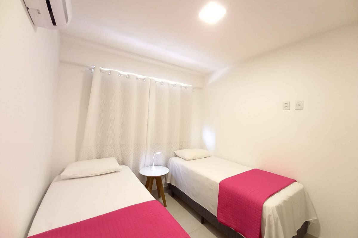 Ein Hotelzimmer mit zwei Betten, einem kleinen runden Tisch, einer Duschvorhang und einer Deckenleuchte.