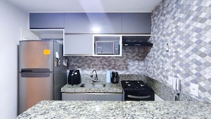 A compact kitchen with a refrigerator, microwave, stove, sink, and a coffee maker. - Flats no Cupe Beach Living (Ipojuca)