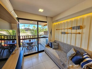 Ein Balkon mit Esstisch und Stühlen, eine Couch mit gemusterten Kissen und zwei Schläger an der Wand.