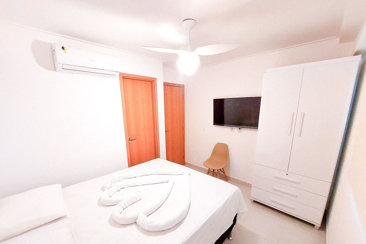 Ein Schlafzimmer mit Bett, Kleiderschrank, Fernseher und Deckenventilator.