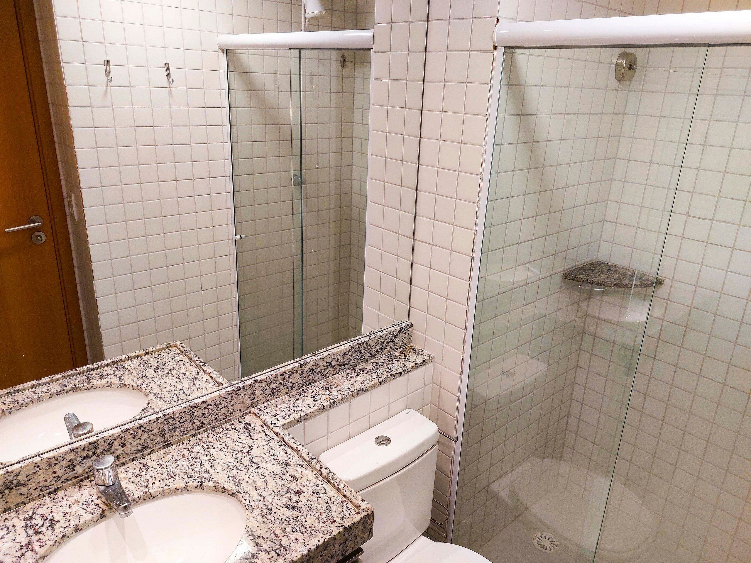 Un baño con dos lavamanos, un inodoro, una cabina de ducha de vidrio y un espejo.