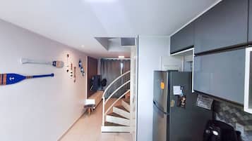 A modern kitchen with a refrigerator, a staircase, and a wall with decorative items.