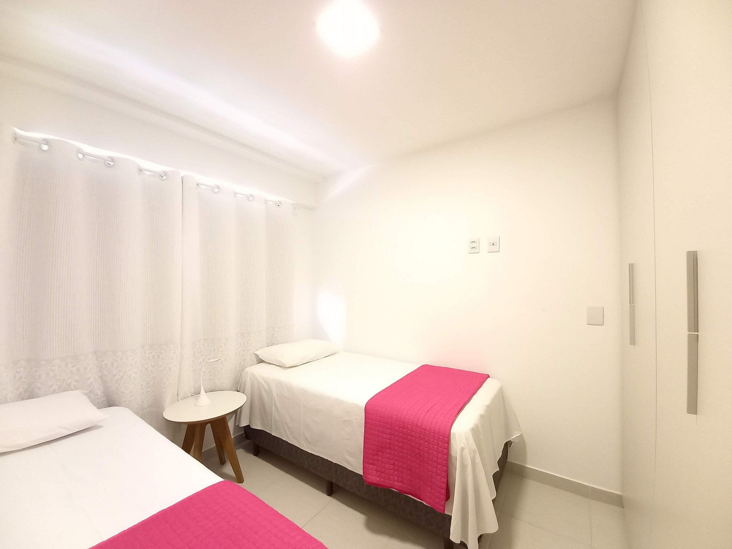 A hotel room with two beds, a small round table, and a shower area.