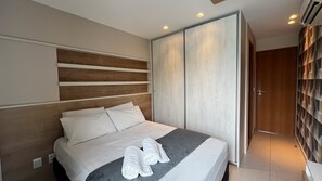 A modern hotel room with a large bed, a wardrobe, and a shower area.