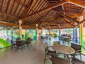A spacious indoor area with high ceilings, wooden beams, and large windows. - Flats no Cupe Beach Living (Ipojuca)