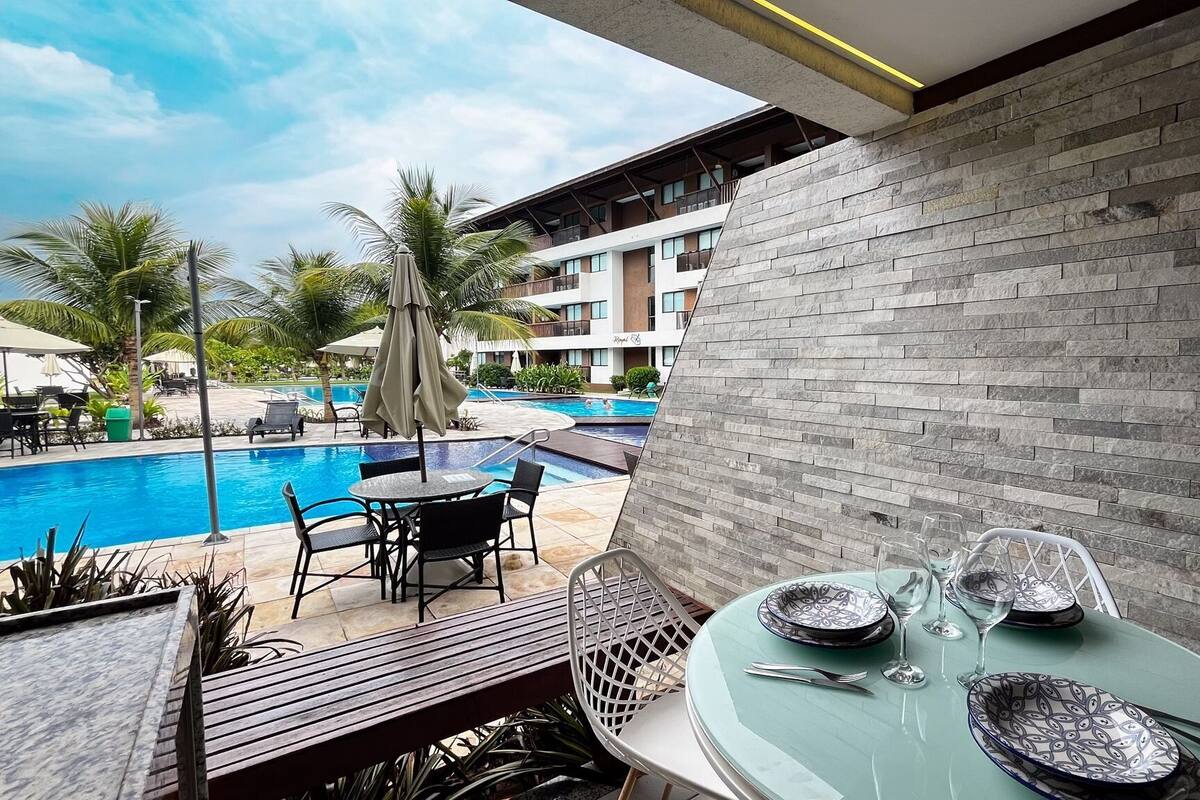 Zona de piscina con mesa lista para comer, una piscina y un edificio de fachada de piedra.