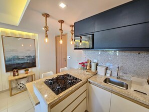 Una cocina moderna con estufa a gas, pileta de acero inoxidable y una isla grande.