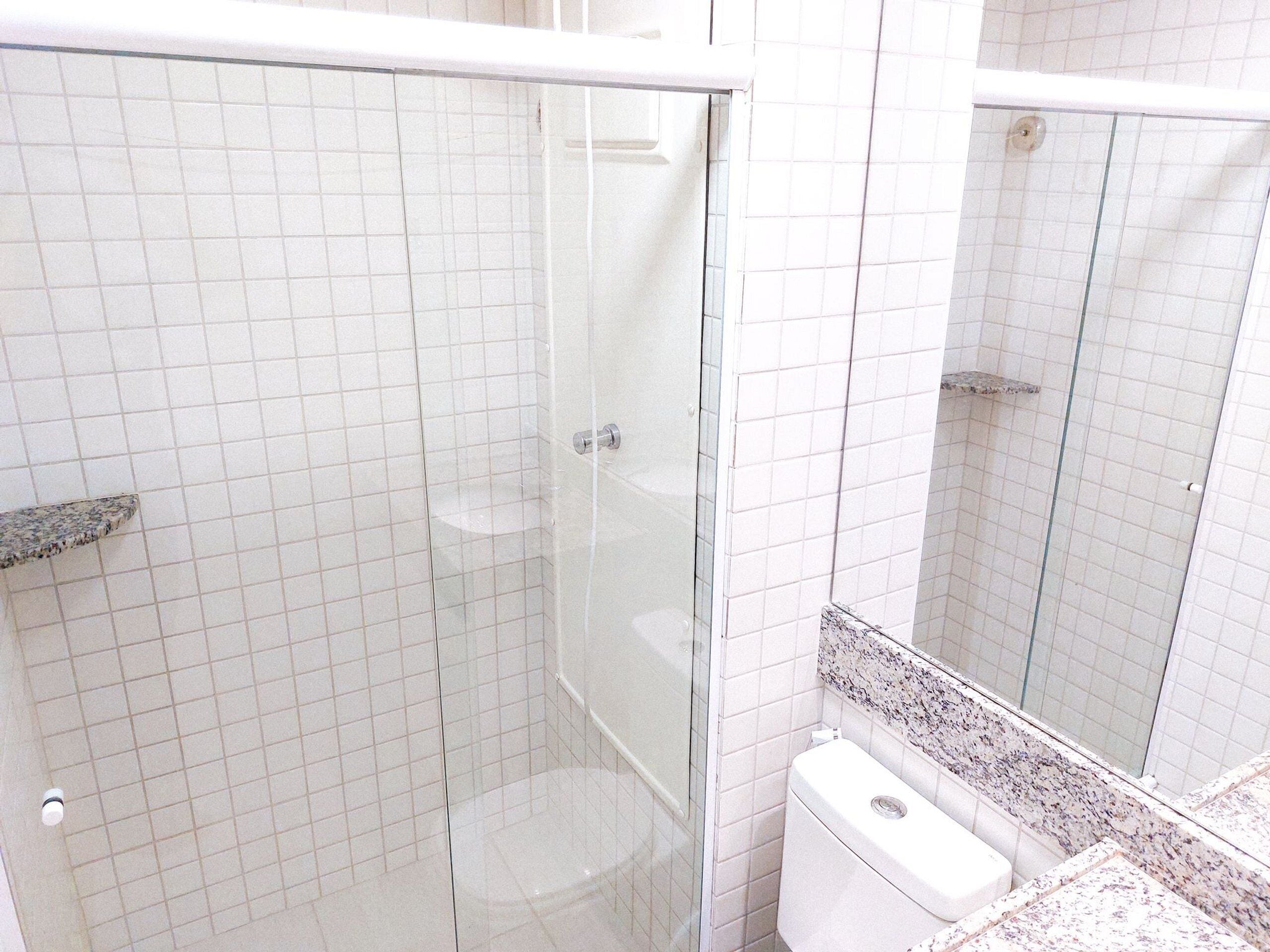 Un bagno con doccia vetrata, un WC bianco e un piano di lavoro in granito.