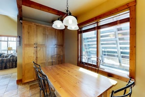Dine in style with a large table surrounded by comfortable chairs, a rustic ceiling, and a window offering a view of the outdoors.