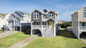 A row of two-story houses with balconies, a covered walkway, and a clear sky. - Paws n Relax 4 Bedroom Home With Private Pool (Kitty Hawk)