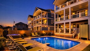 A two-story house with a swimming pool, outdoor furniture, and a wooden deck. - Eleanor Dare 8 Bedroom Oceanfront Home, Cabana Service, Private Pool & Pet Friendly (Nags Head)