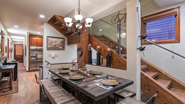 A spacious kitchen with a large island, wooden beams, and a modern chandelier. - Columbine House (Telluride)
