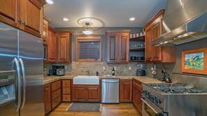 A modern kitchen with wooden cabinets, stainless steel appliances, and a central island. - Columbine House (Telluride)
