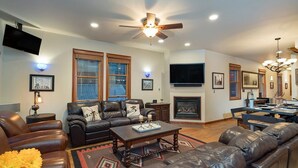 A spacious living room with a leather sofa, a coffee table, and a fireplace. - Columbine House (Telluride)