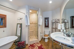 A bathroom with a bathtub, two sinks, a toilet, a shower, and a mirror.