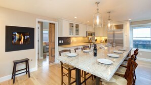 A modern kitchen with a large island, wooden chairs, and pendant lighting. - Christel - Peaceful West End Home, Downtown Telluride, Walk to Ski (Telluride)