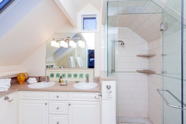 A modern bathroom with two sinks, a large mirror, and a glass-enclosed shower.