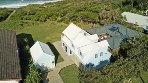 Zona residencial costera con casas, un jardín con césped y vista al océano.