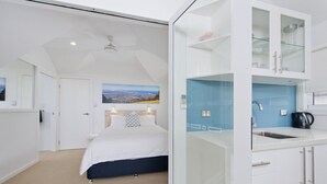 Habitación de hotel moderna con cama, baño con cabina de ducha de vidrio y vistas al paisaje a través de la ventana.