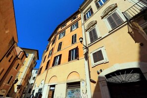 Une rue étroite bordée d’immeubles aux fenêtres en arc et aux balcons.