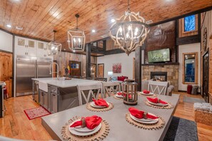 Una cucina moderna con un'isola grande, elettrodomestici in acciaio inossidabile e un'area pranzo per quattro persone apparecchiata con tovaglioli rossi.