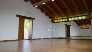 Una habitación amplia con vigas de madera y un techo alto, que cuenta con un espacio abierto y una puerta que da al exterior.