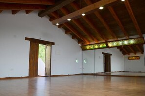 A spacious room with wooden beams and a high ceiling, featuring a large open area and a door leading outside. - Los Ahijaderos de Tus - Casa La Higuera 3 hb (Yeste)