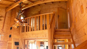 A wooden cabin interior with a loft bedroom, a staircase, and a kitchen area. - Homerez - Chalet in La Bresse (La Bresse)