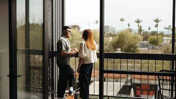 Una pareja parada en un balcón con vistas a palmeras y edificios.
