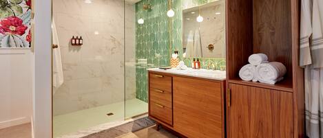 A modern bathroom with a glass shower enclosure, wooden vanity, and a mirror with a wooden frame.