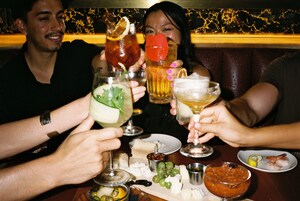 Um grupo de pessoas brindando com bebidas em um restaurante.