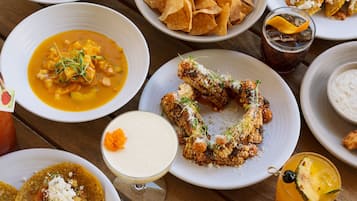A variety of dishes including tacos, a bowl of soup, and a plate of corn on the cob.