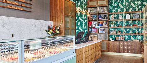 Une vitrine à bijoux contenant divers articles, un comptoir en bois et un mur orné d’un motif végétal vert.