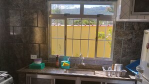 Una cocina compacta con ventana, estufa, armarios y refrigerador.